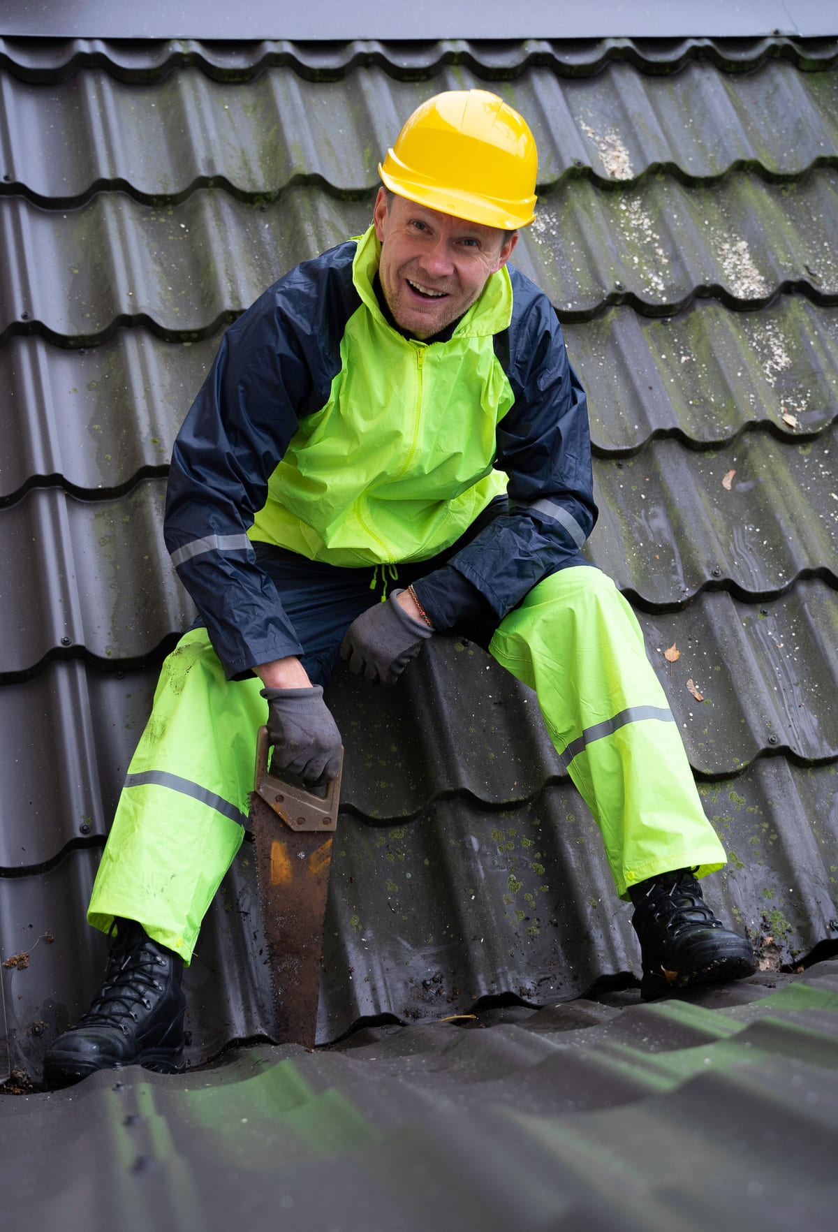 A worker wearing a hard hat while working on a tiled roof.