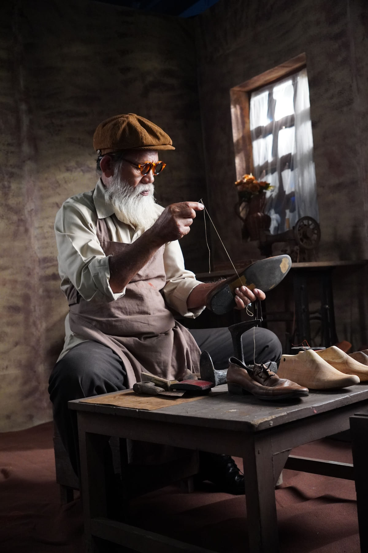 A cobbler working on a shoe at a bench in a traditional workshop.