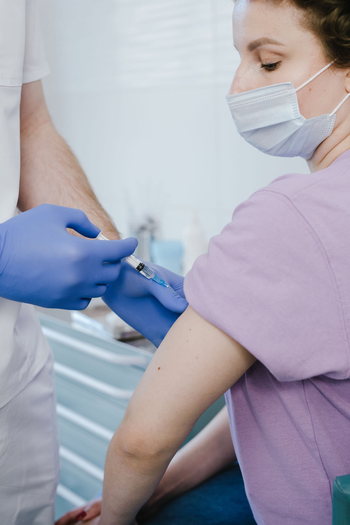 A healthcare worker administering an injection into a patient's upper arm.