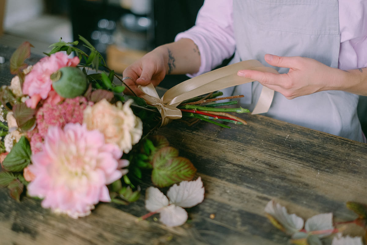 A florist wrapping a colorful bouquet at a worktable.