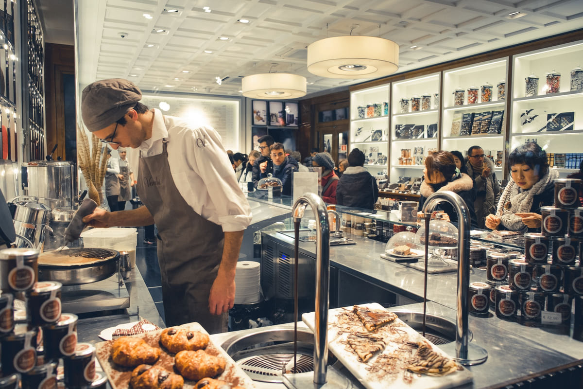 Bakery staff serving behind a counter filled with bread and pastries.