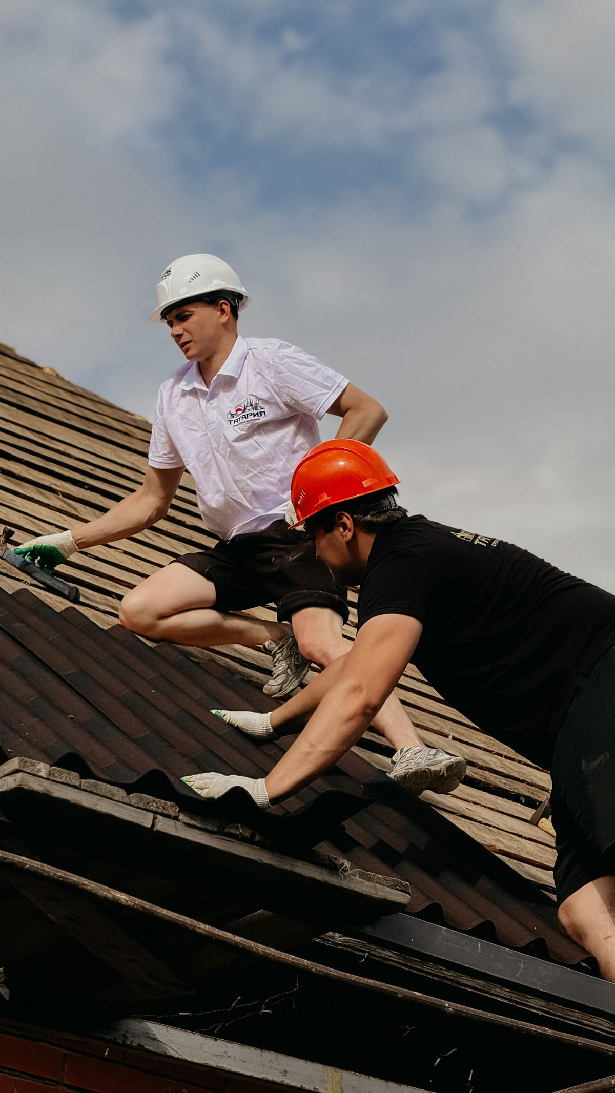 Two workers inspecting a tiled residential roof.