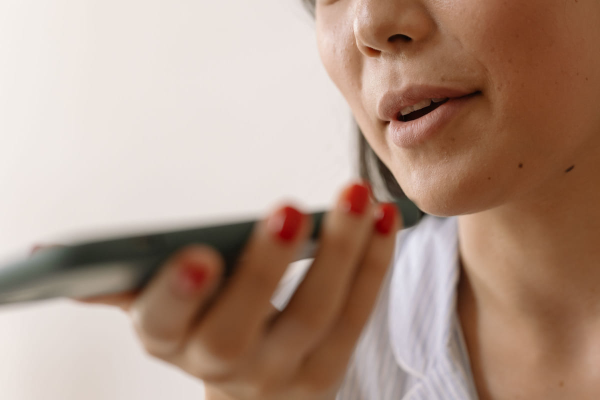 A woman speaking toward her smartphone's microphone.