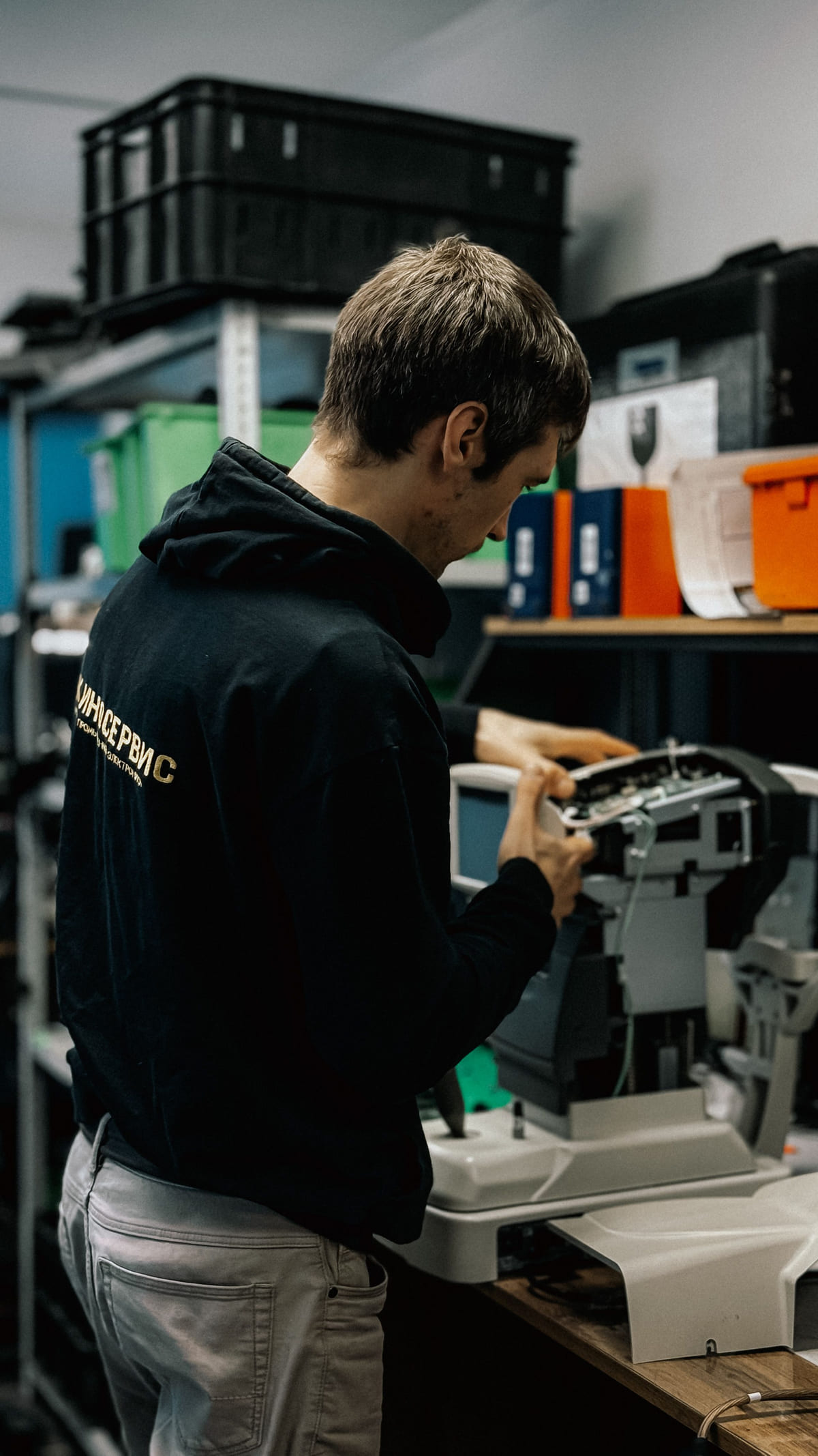 A technician working on an open office printer at a repair bench.