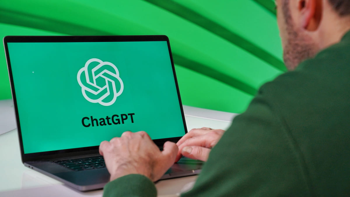 A person using a laptop with a ChatGPT logo displayed on its screen.