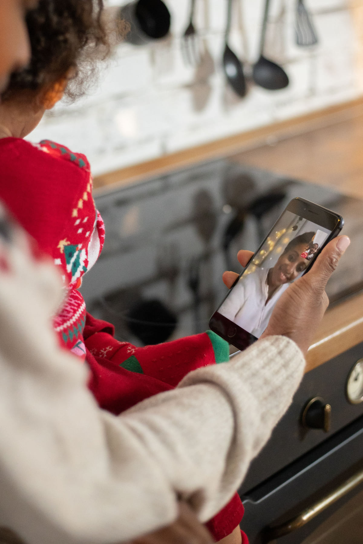 A person checking a smartphone beside a kitchen stove.