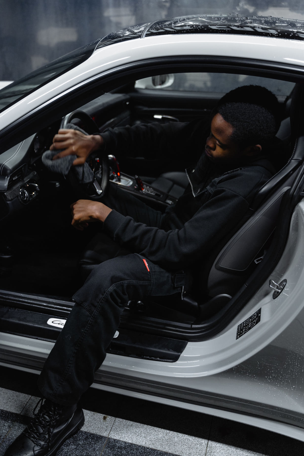 A worker cleaning the inside of a car through an open door.