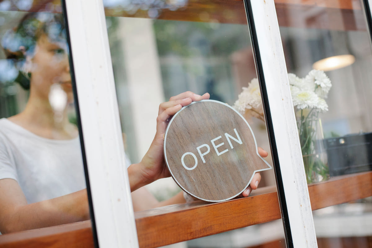 A café worker putting an open sign in a window.