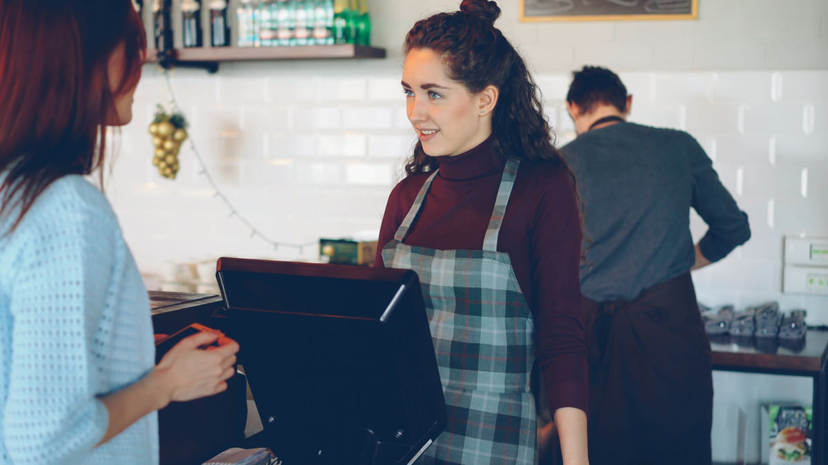 A barista serving a customer at a café counter.