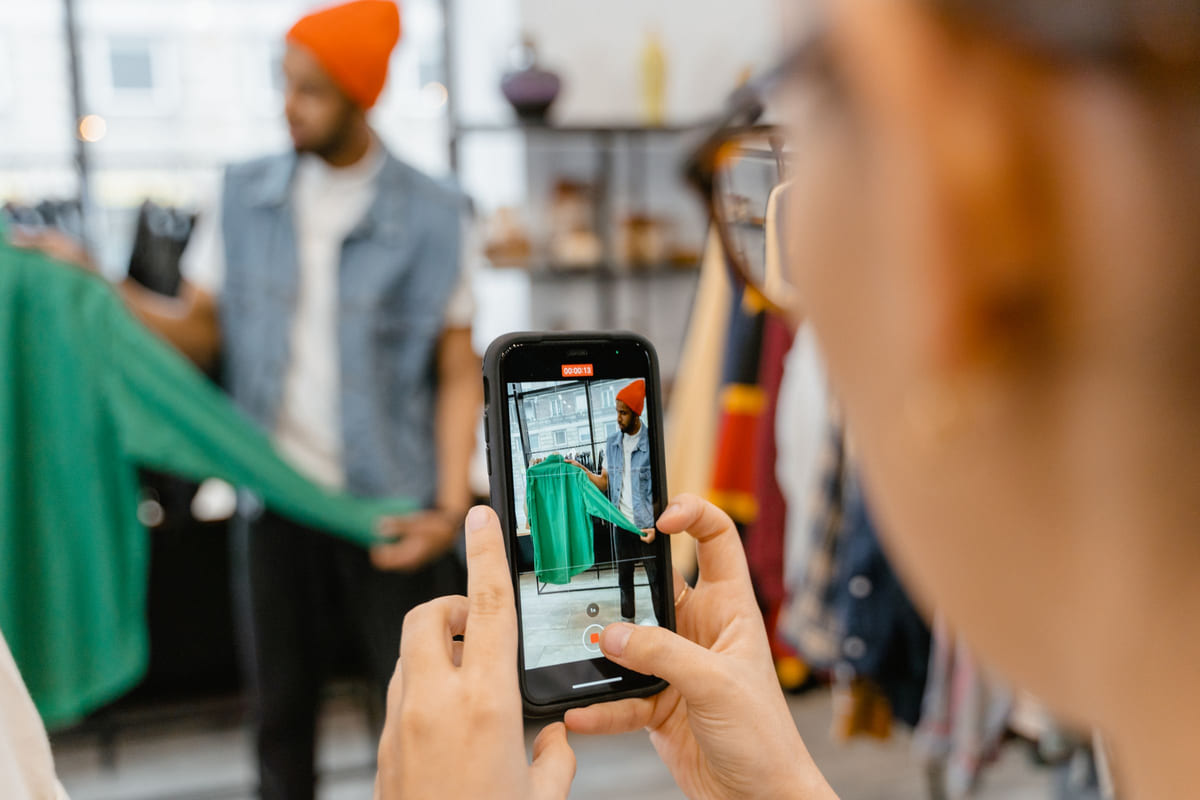 A customer using a smartphone to photograph an outfit inside a clothing shop.
