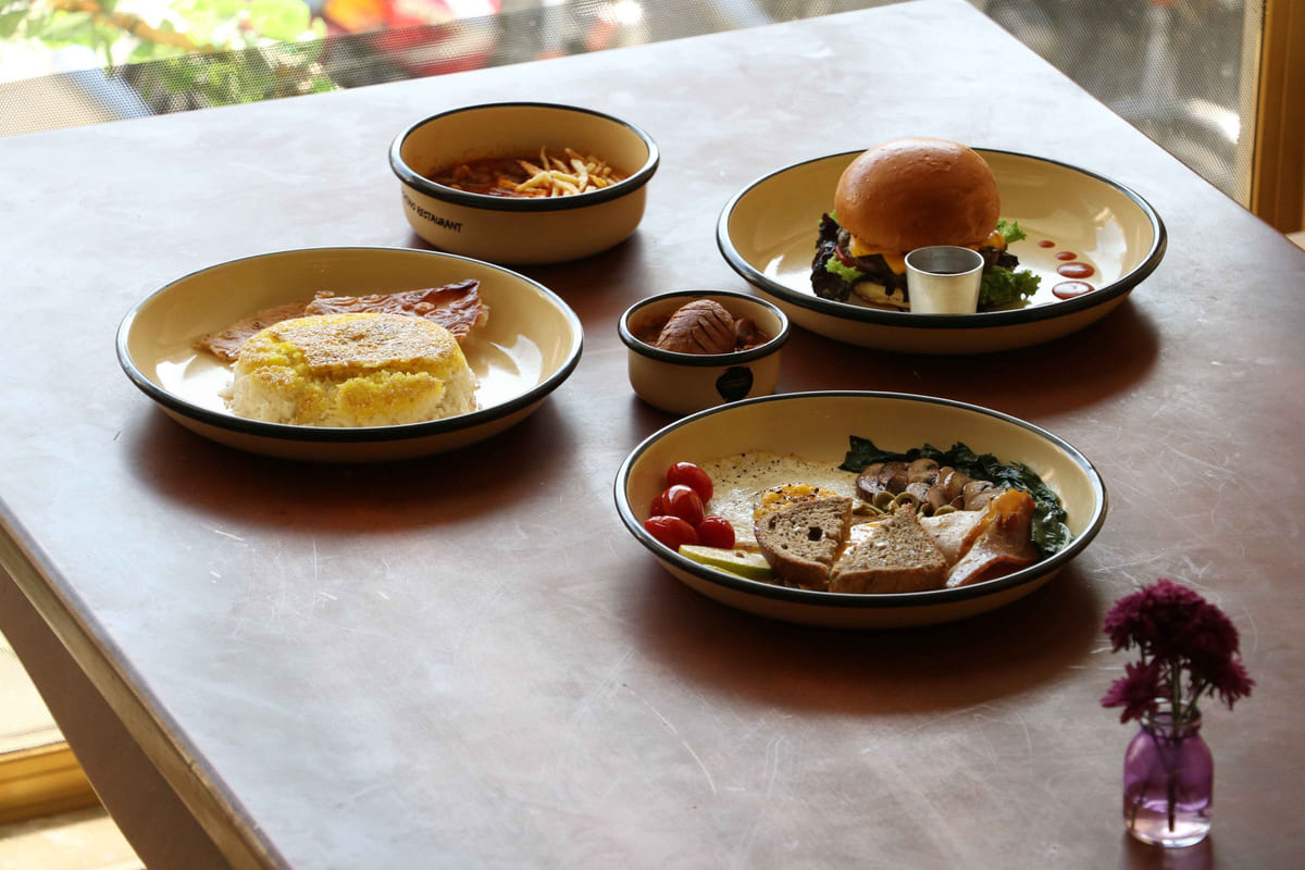 Several plated restaurant dishes arranged on a table in natural light.