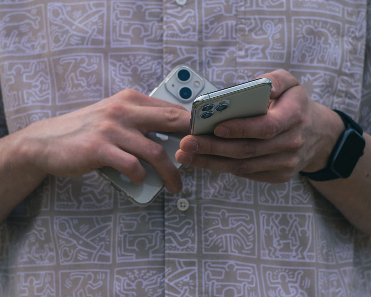 A person comparing two smartphones held side by side.