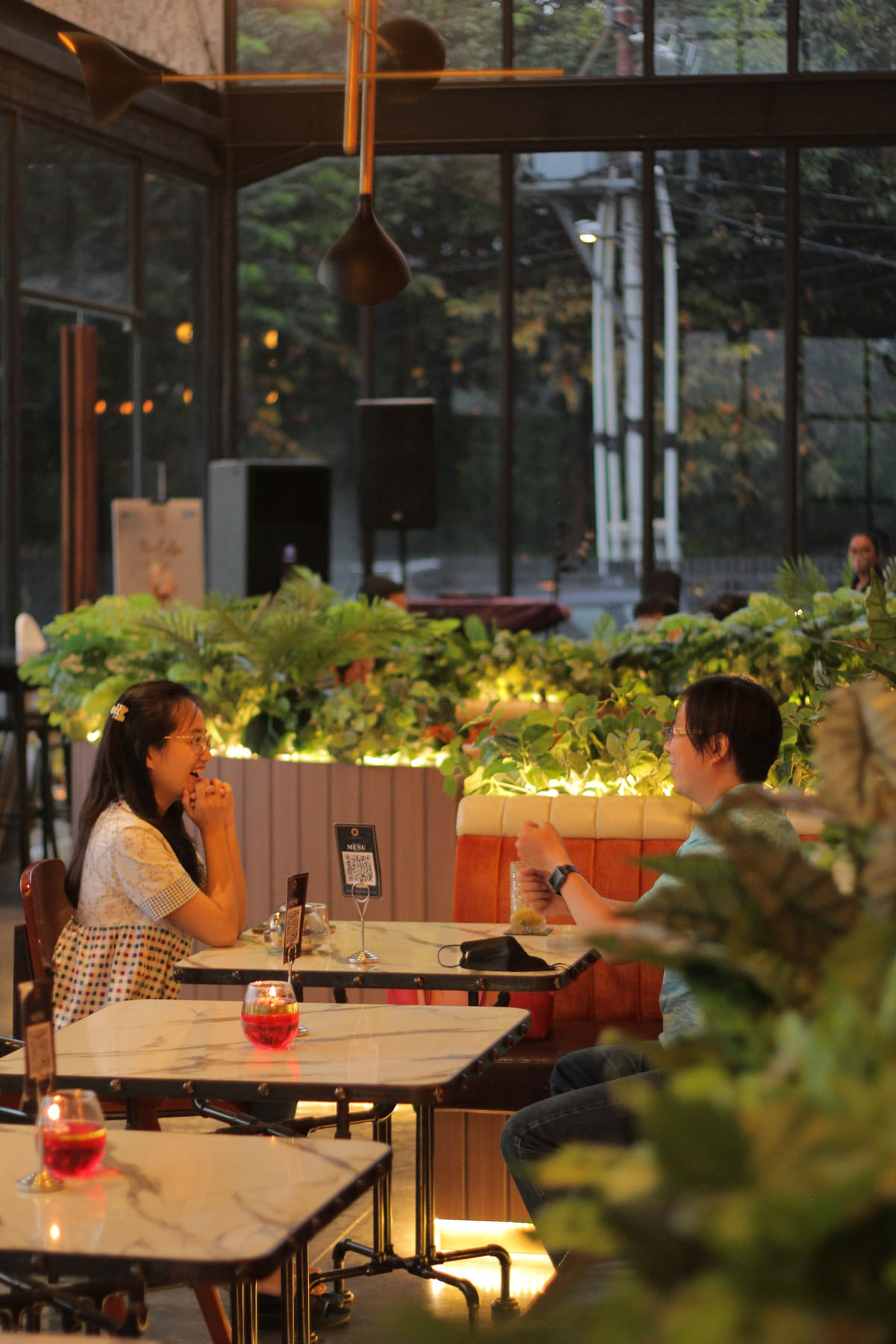 Two people dining beside a window in a softly lit restaurant.