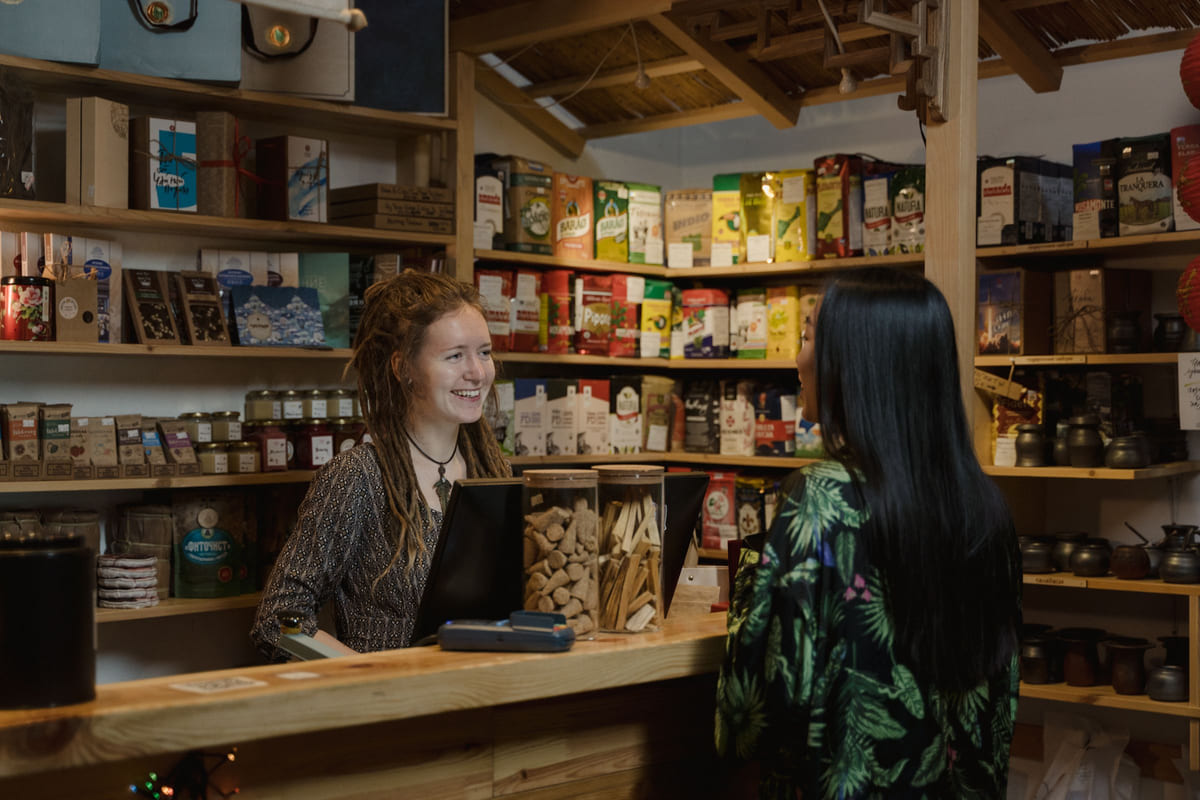 A shopkeeper helping a customer across a wooden counter.