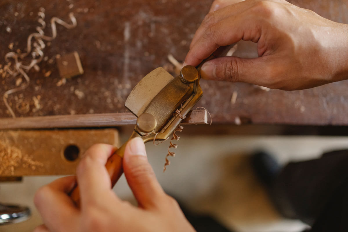 A craftsperson shaping wood with a hand plane.